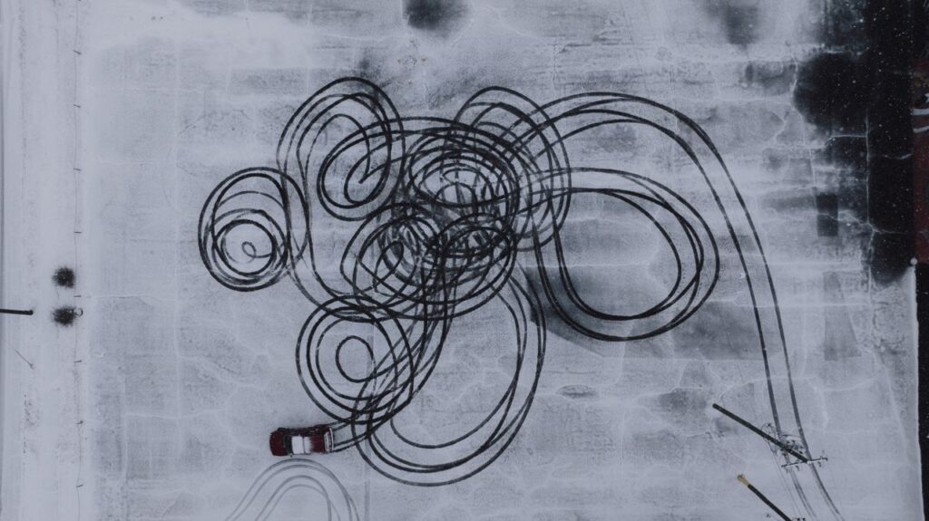 Aerial shot showing intricate tire tracks on a snowy surface, showcasing winter driving patterns.